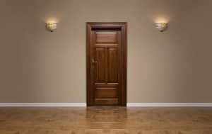 Braune massive Holztür, zwei Wandlampen, Holzboden, beige Wandfarbe