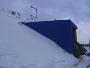 Tipp zum Bau zeigt den Einbau einer Flachdachgaube auf einem mit Schnee bedecktem Hausdach.